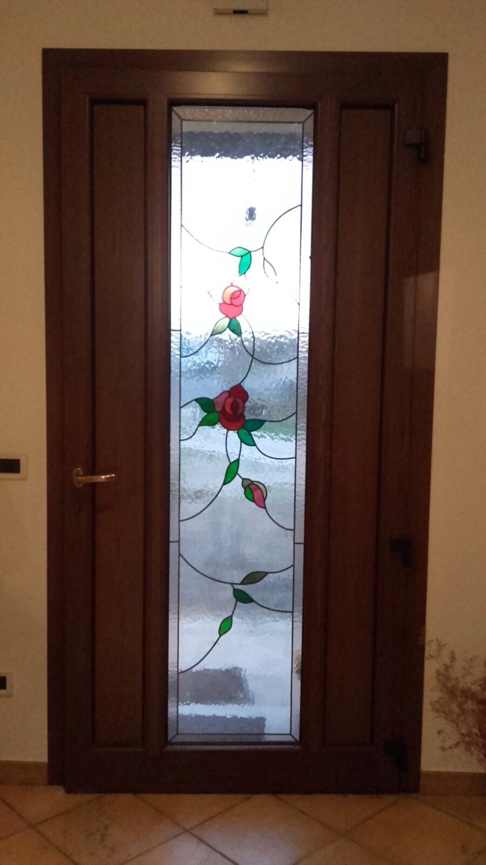 Una porta con una vetrata decorata con delle rose.