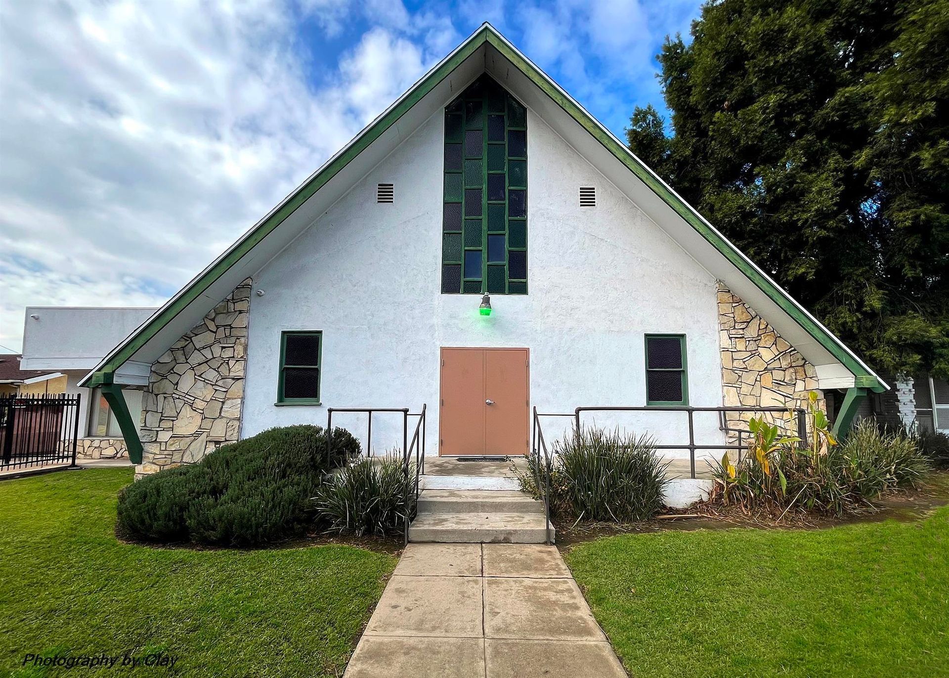 A white building with a brown door and green windows