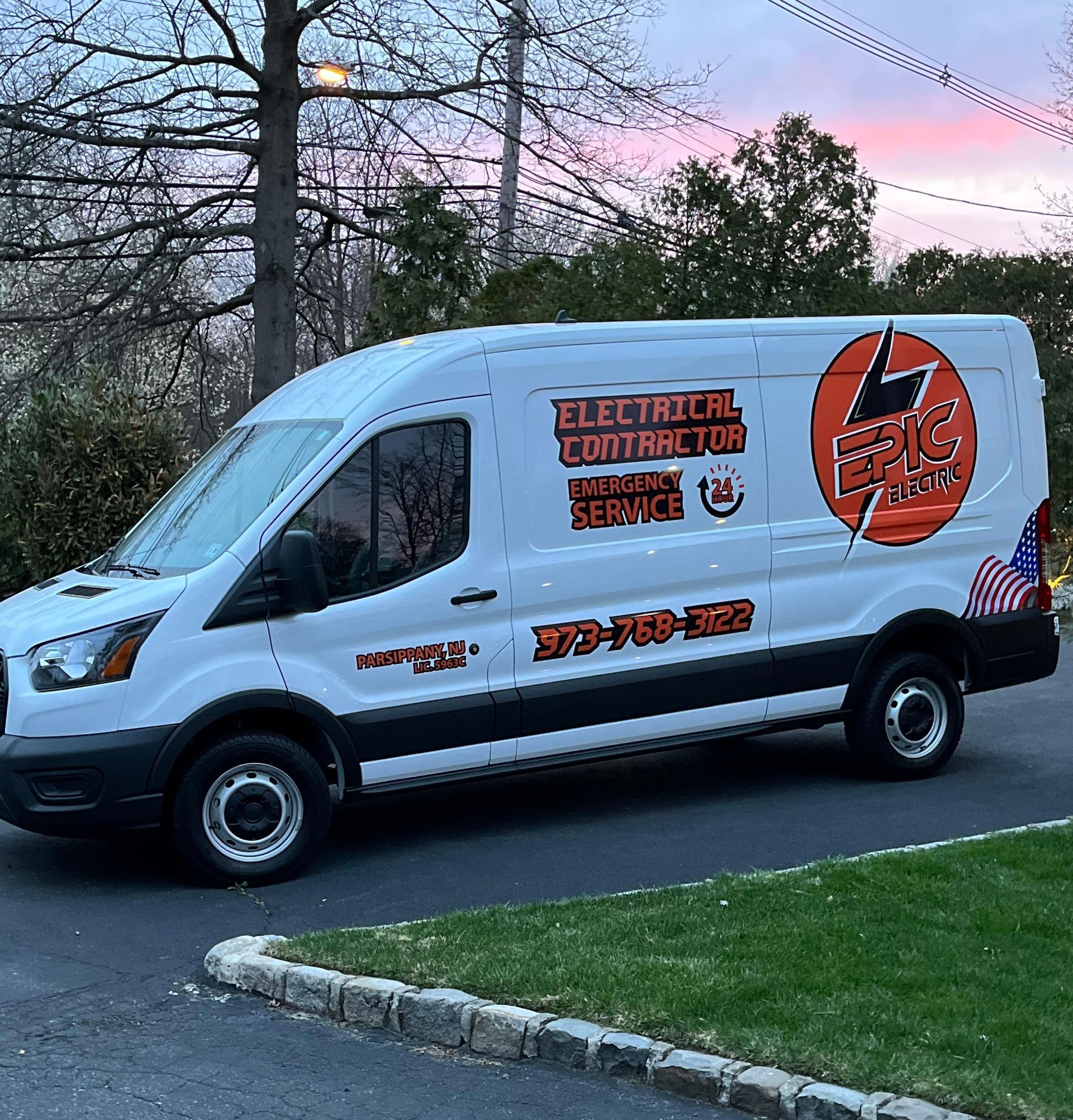 A white electrical contractor van is parked on the side of the road.