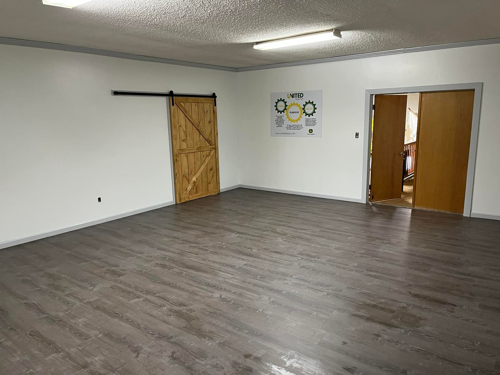 Woman in straw hat smiles, holding wine glass near a lake.