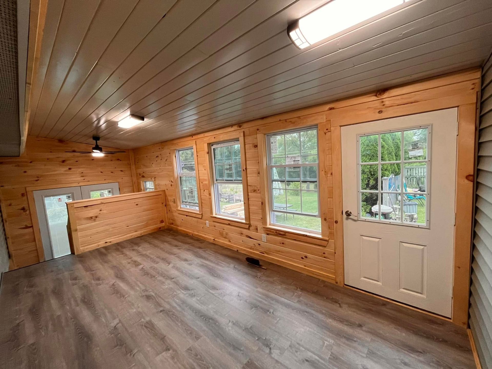 Woman in straw hat smiles, holding wine glass near a lake.