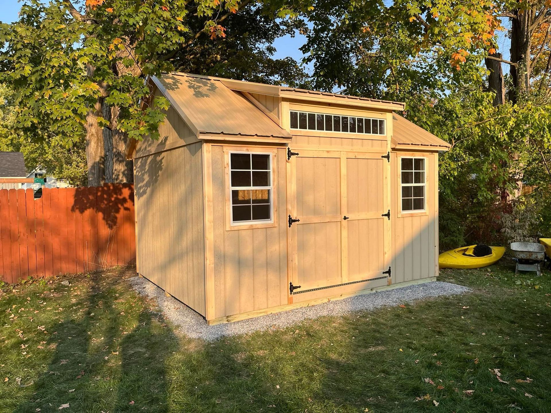 Woman in straw hat smiles, holding wine glass near a lake.