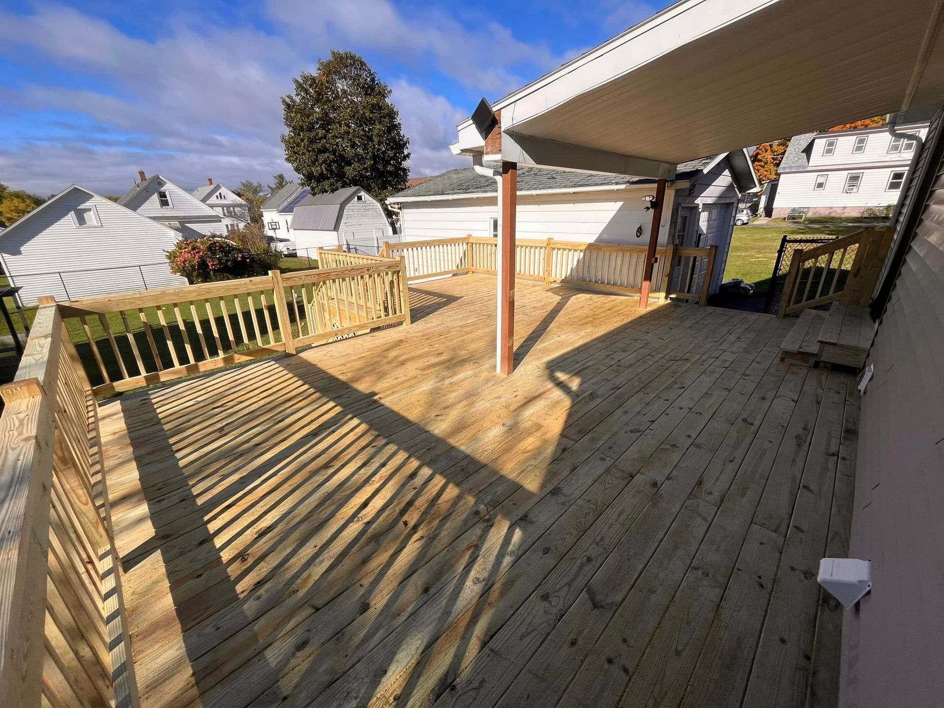 Woman in straw hat smiles, holding wine glass near a lake.