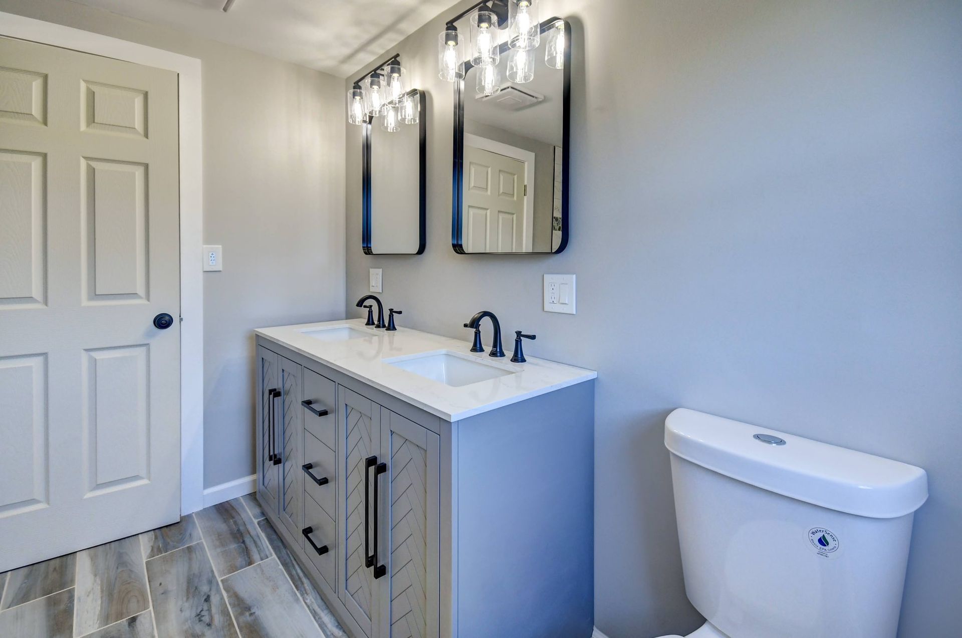 Woman in straw hat smiles, holding wine glass near a lake.