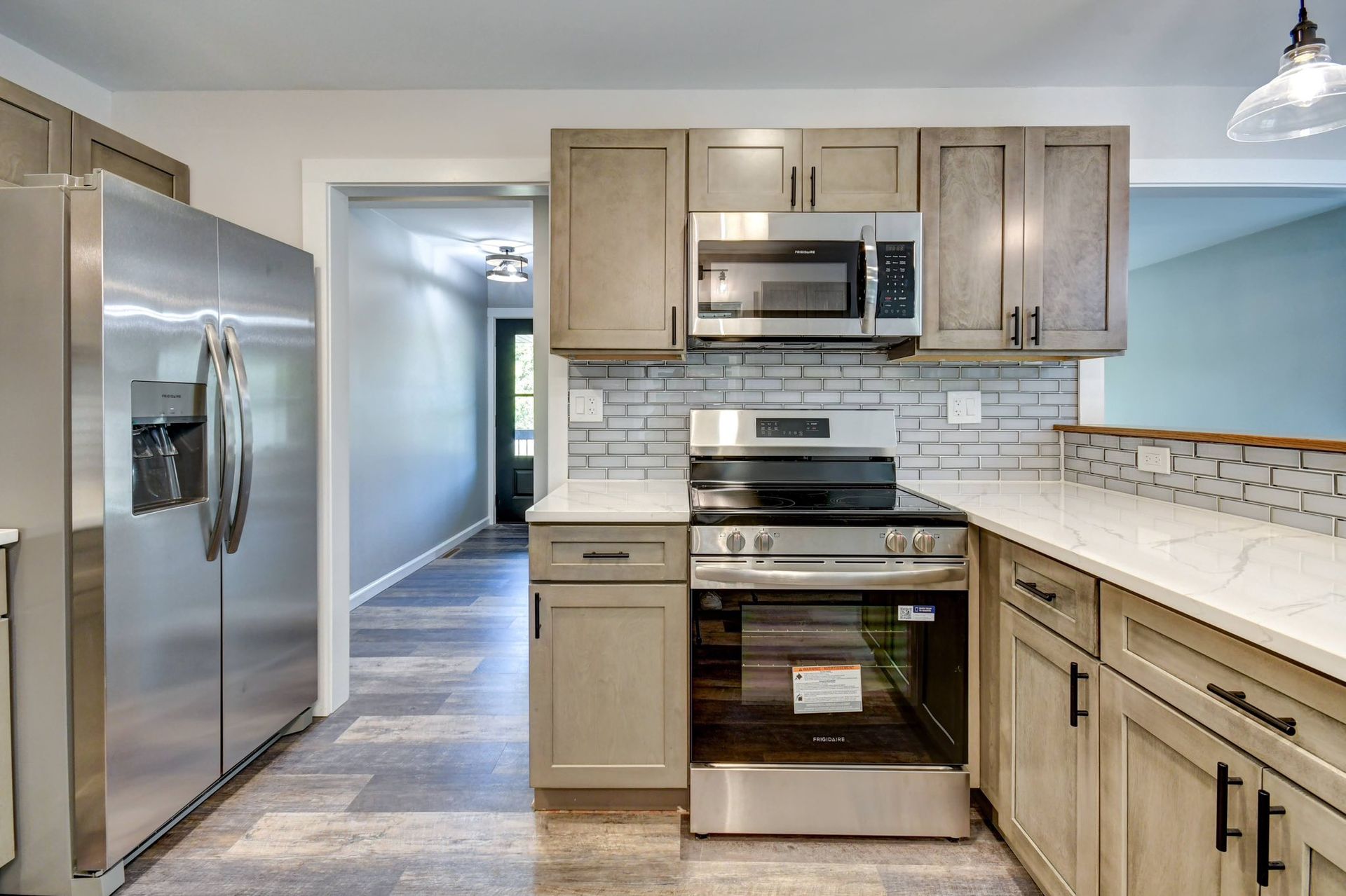 Woman in straw hat smiles, holding wine glass near a lake.