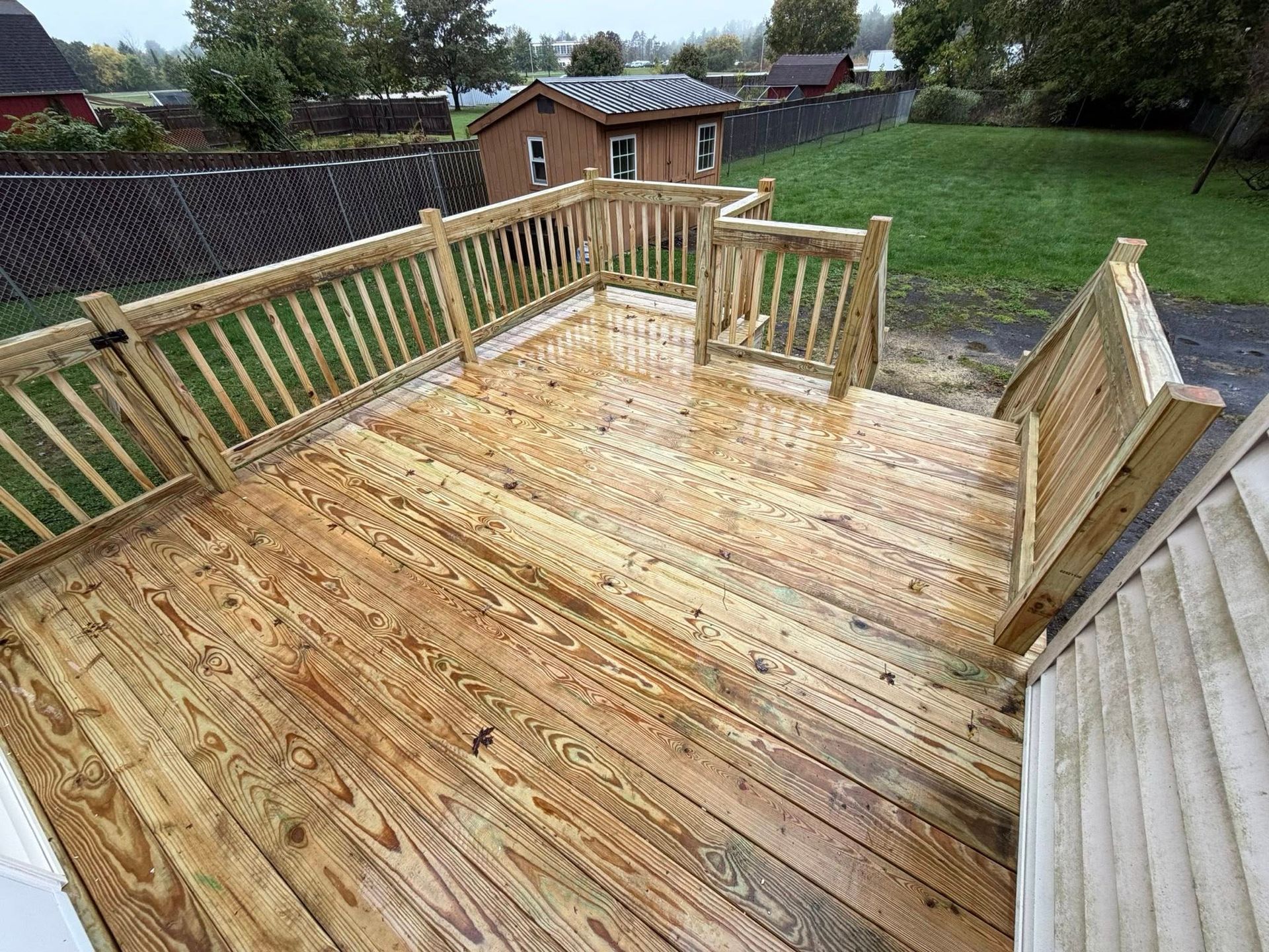 Woman in straw hat smiles, holding wine glass near a lake.