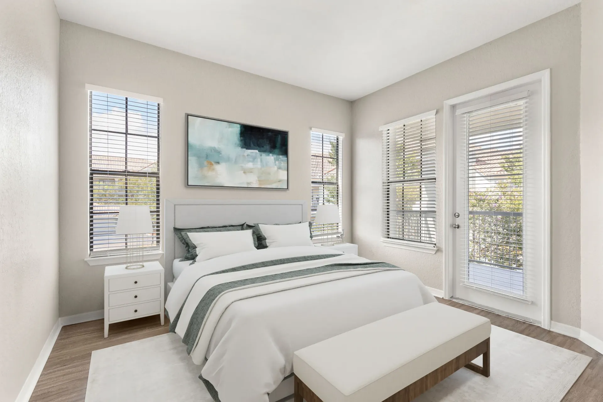 A bedroom with a large bed, a nightstand, a bench, and a painting on the wall.