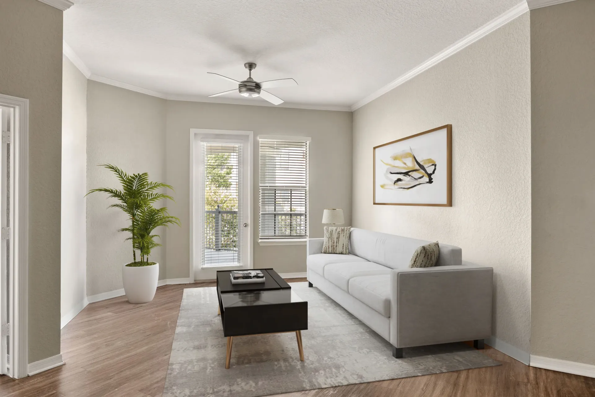A living room with a grey couch, a coffee table, a plant, and a painting on the wall at Levi at River City.