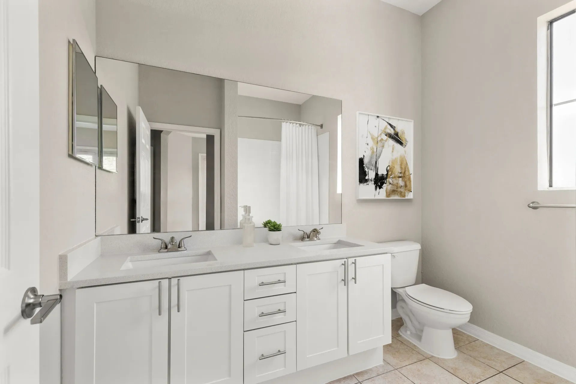 A white bathroom with a double sink and a toilet.