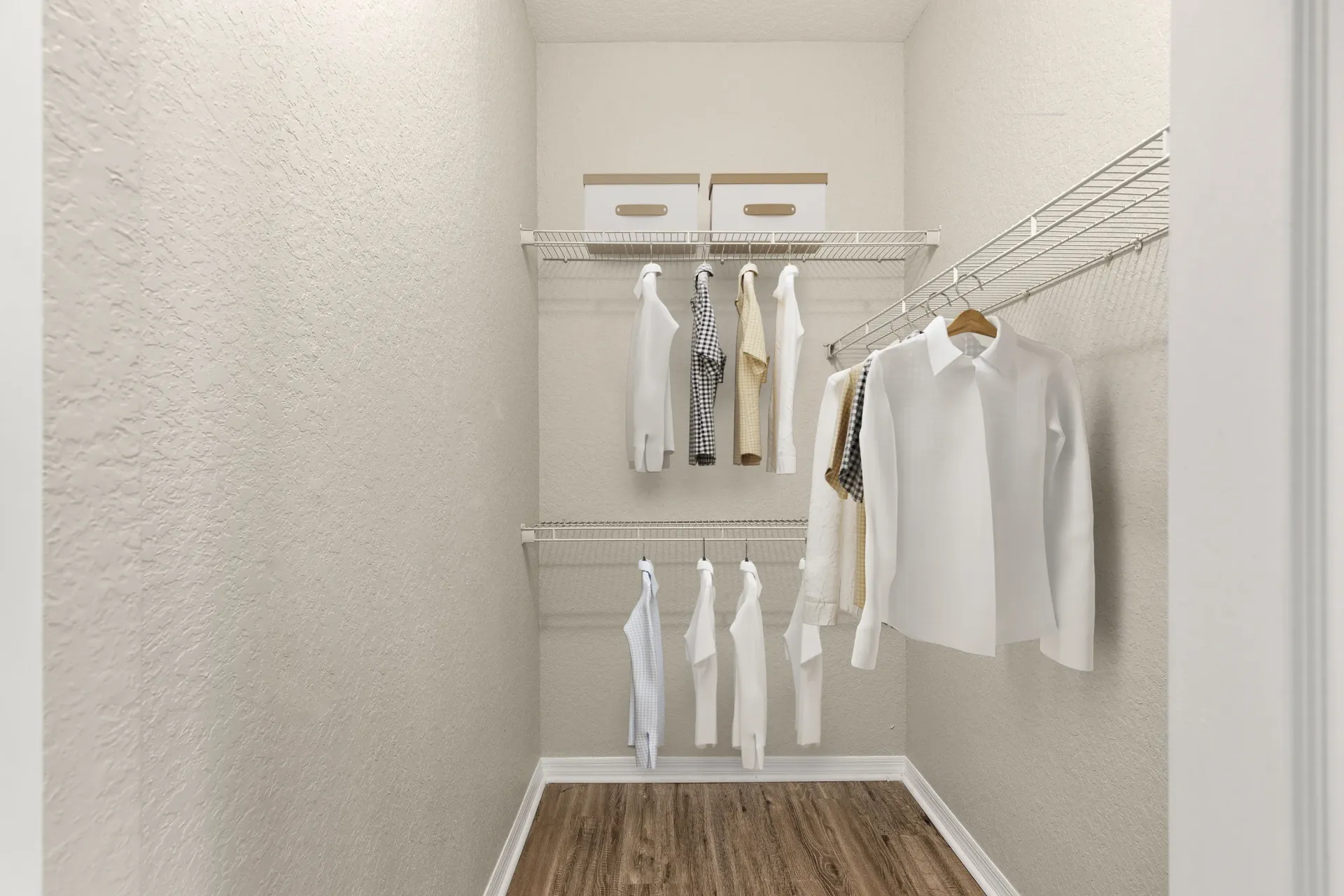 A white closet with clothes hanging on a wire rack.