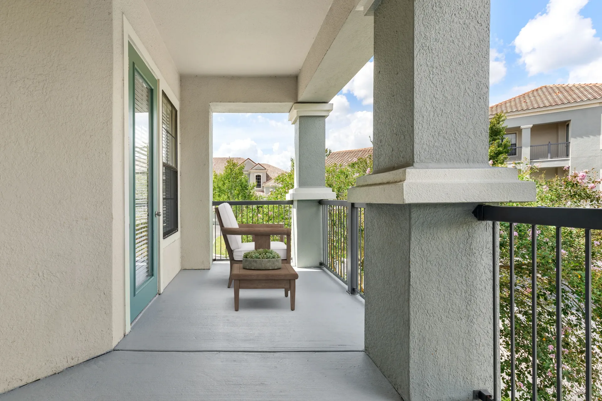 A balcony with a chair and a table with a plant on it.