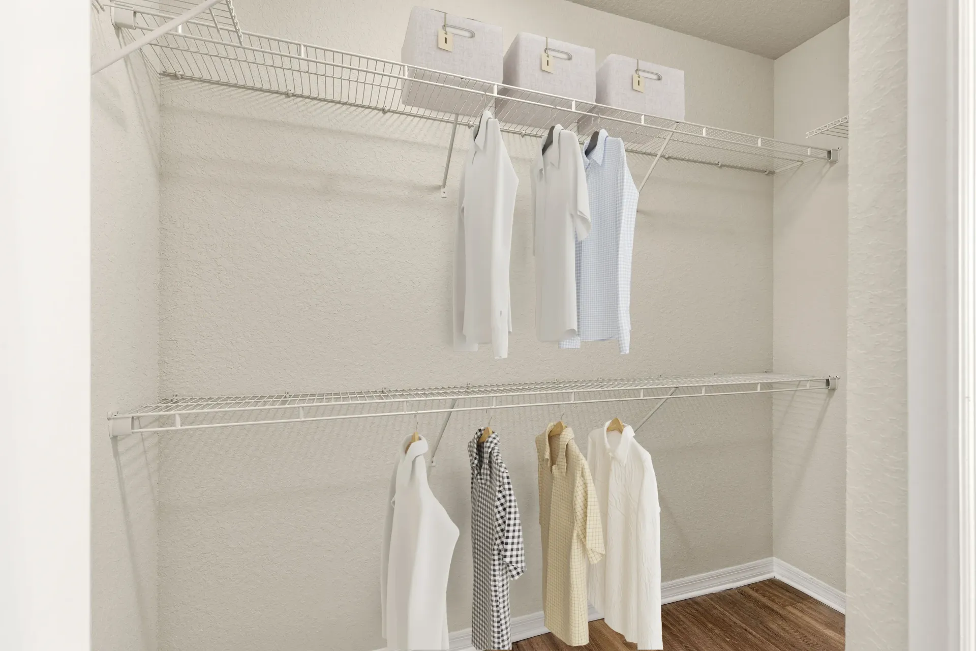 A white closet with clothes hanging on hangers.