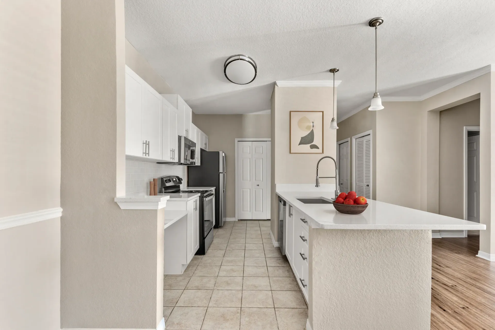 A kitchen with white cabinets and a white island with a bowl of strawberries on it.