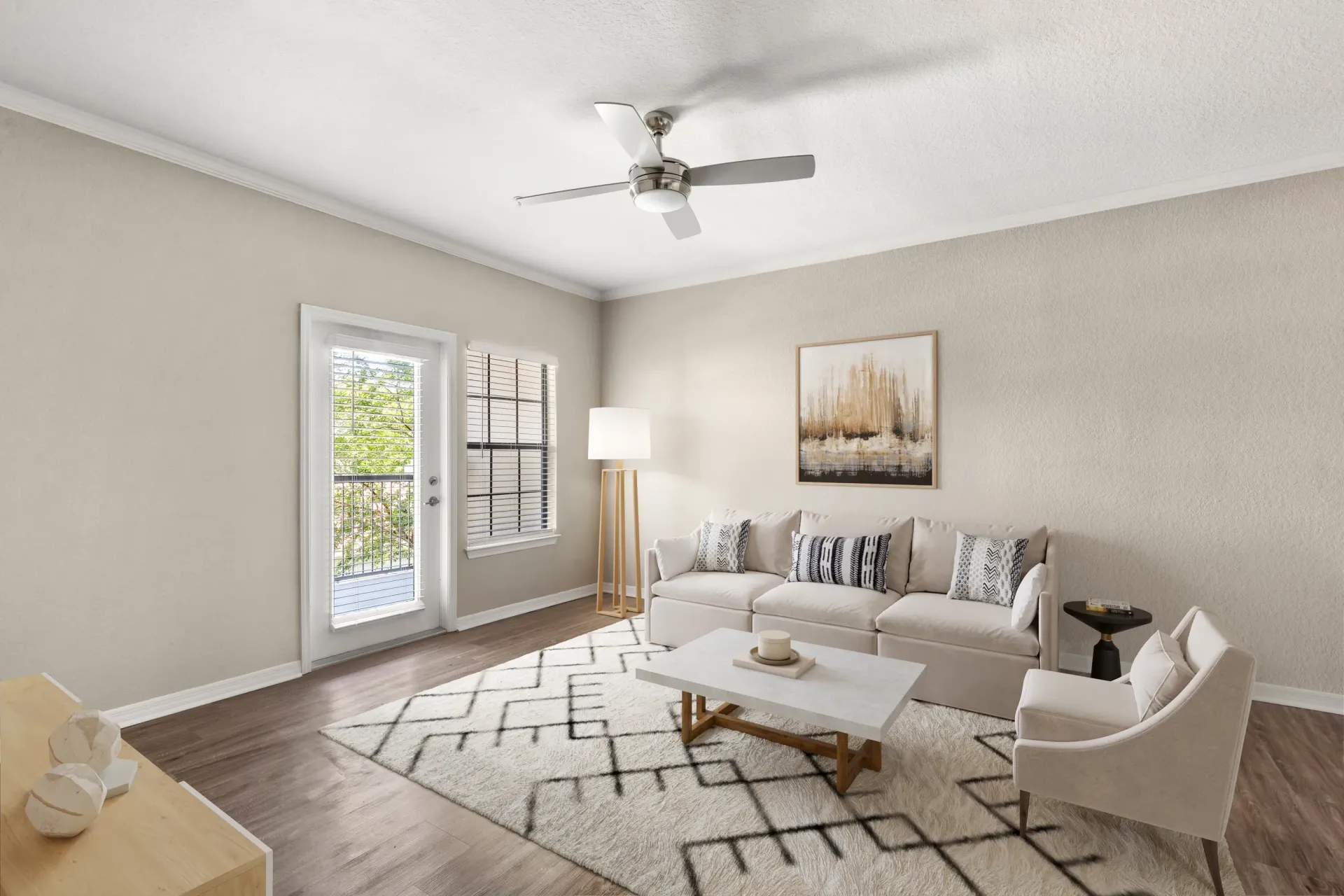 Bright living room with white sofa, armchair, coffee table, floor lamp, ceiling fan, and glass doors at Levi at River City.