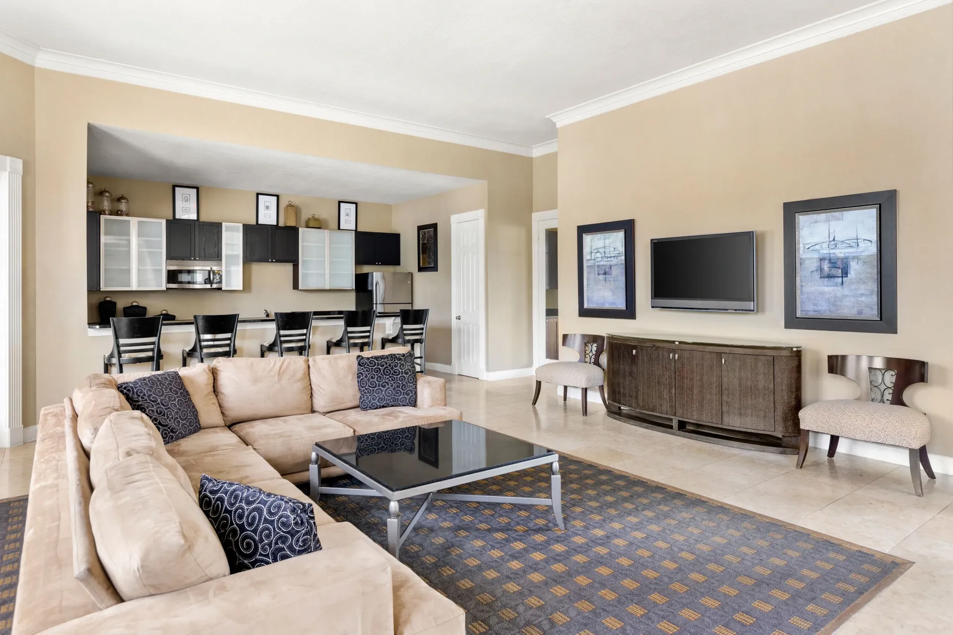 A living room with a tan couch and a glass coffee table.