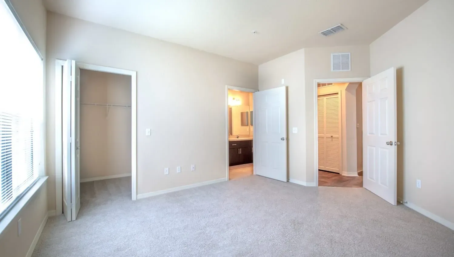 A spacious room with carpeted floor and white walls at Levi at River City.