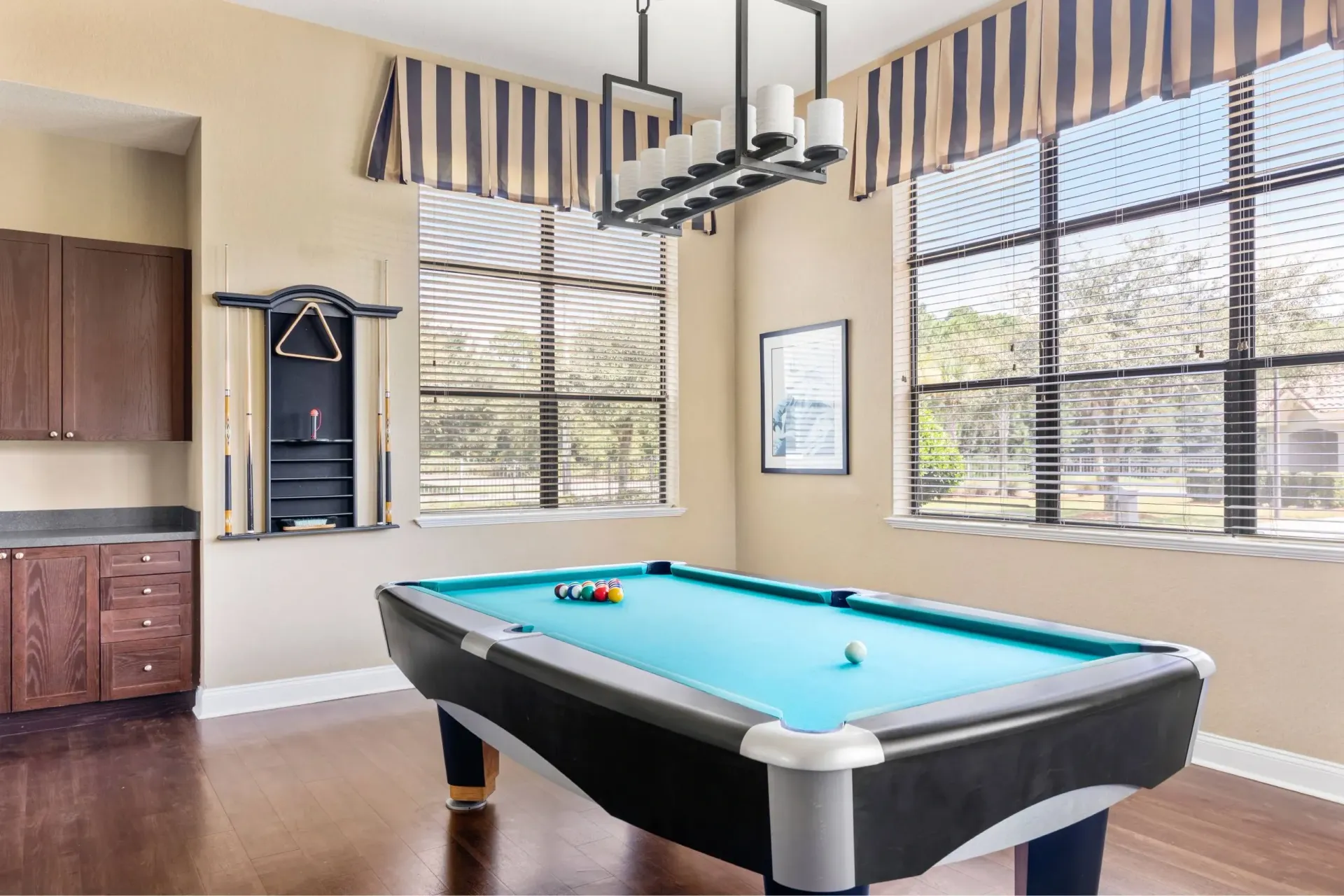 A pool table in a room with a window and a cabinet at Levi at River City.