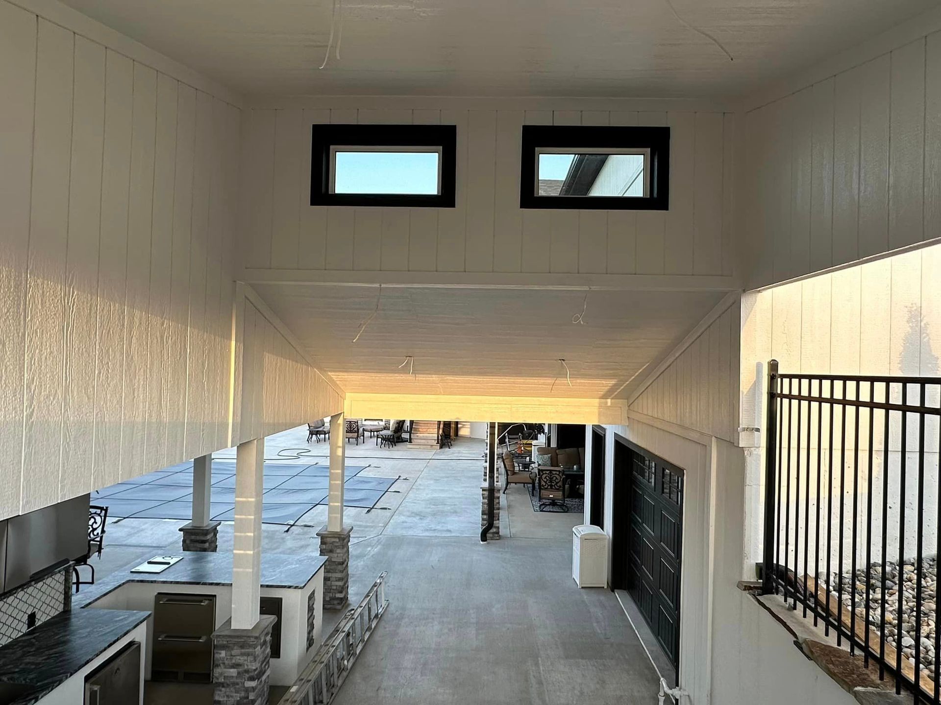 A walkway leading to a garage with two windows and a fence. Big T Construction.