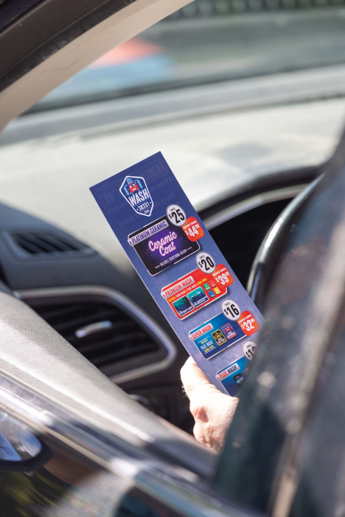 A person is holding a menu in their hand while sitting in a car.