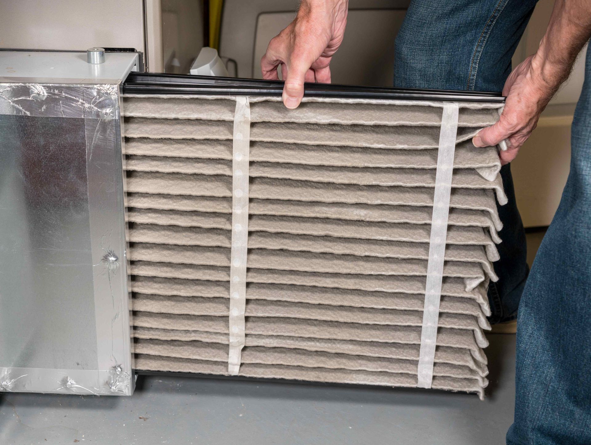 A man changing ac unit filter during a tune up