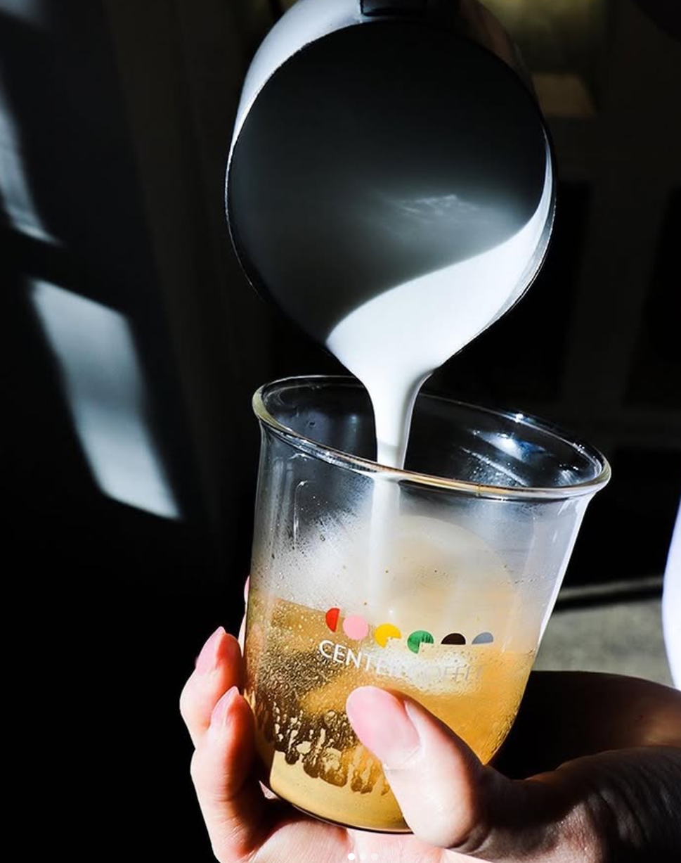 Milk being poured into espresso at Center Coffee near Seoul Forest, captured in a clear branded cup with dramatic lighting
