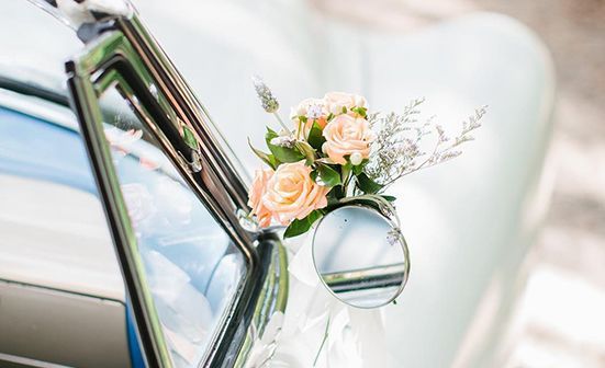 A close up of a car with flowers in the side mirror.