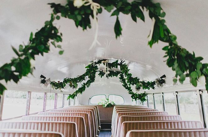 The inside of a bus decorated with greenery and flowers for a wedding ceremony.