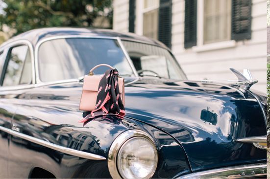 A black car with a pink purse hanging from the hood.