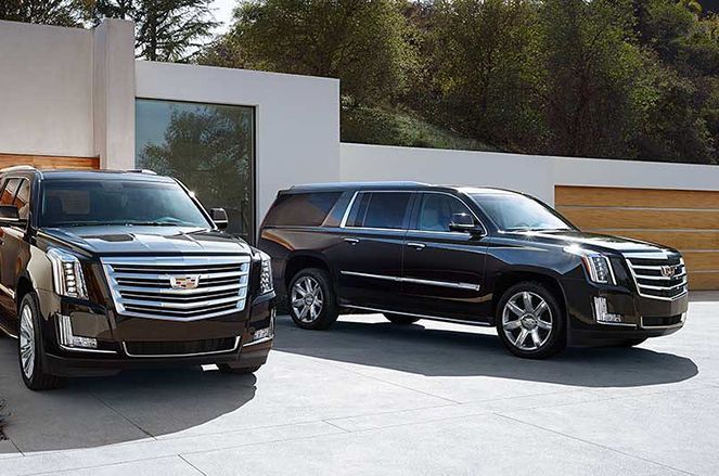 Two cadillac suvs are parked next to each other in a driveway.