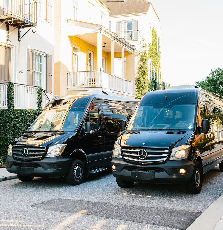 Two black mercedes vans are parked in front of a house