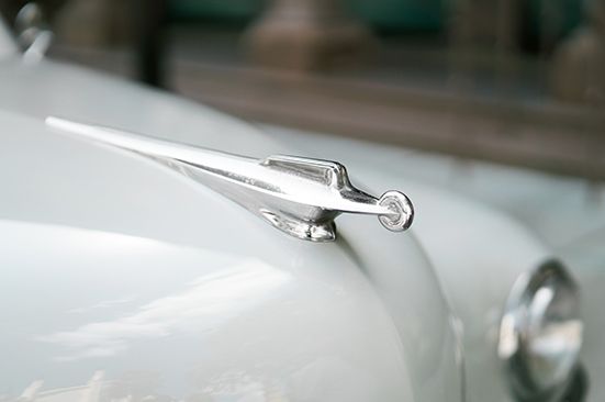 A close up of a car hood ornament on a white car