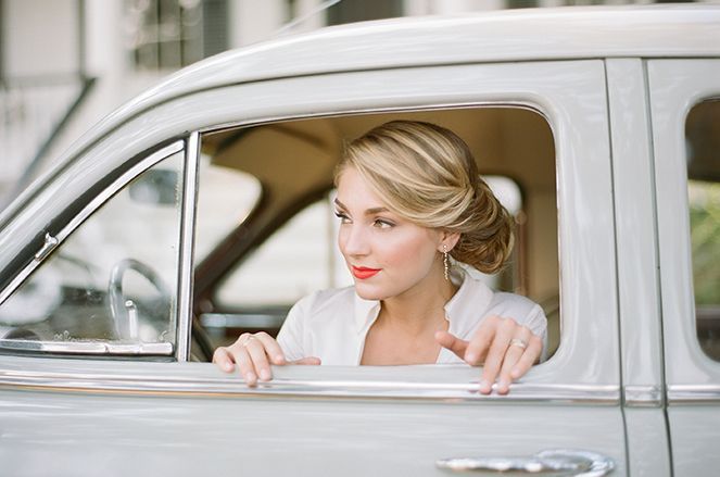 A woman is sitting in a white car looking out the window.