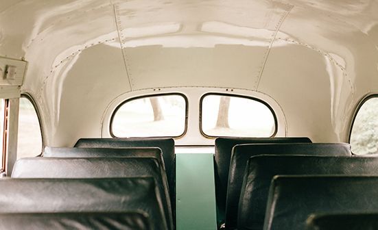 The inside of a bus with empty seats and a window.