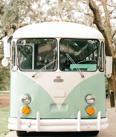 A green and white bus is parked on the side of the road.