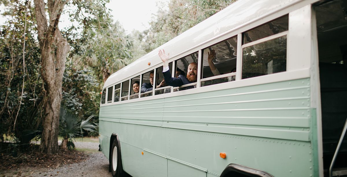 A bus with people riding on it is parked next to a tree.