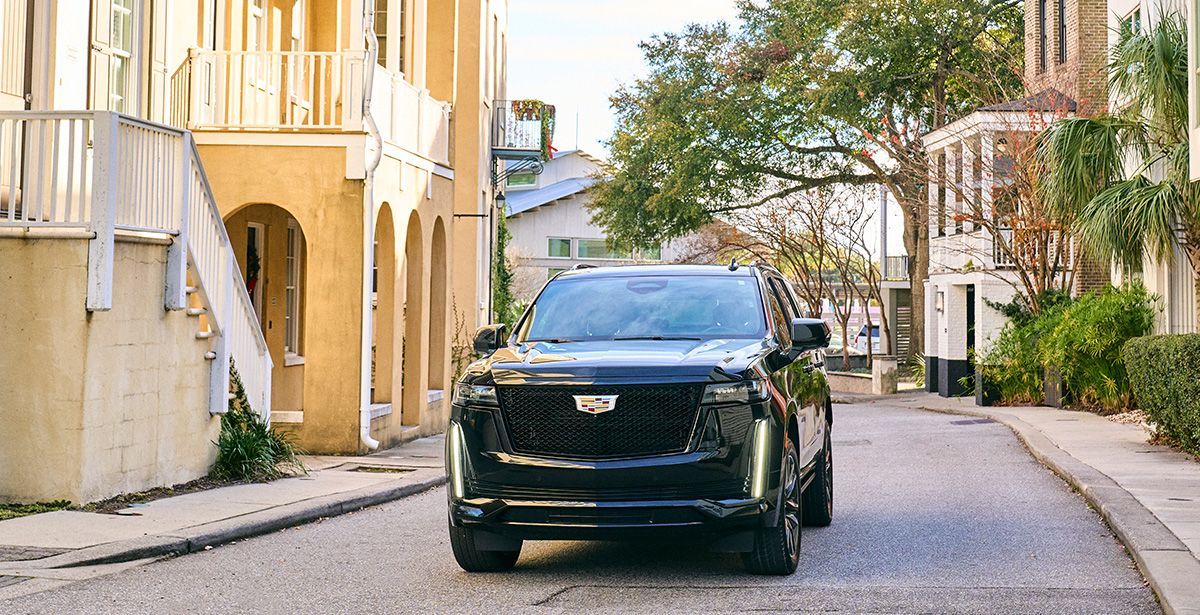 A black cadillac escalade is parked on the side of a city street.