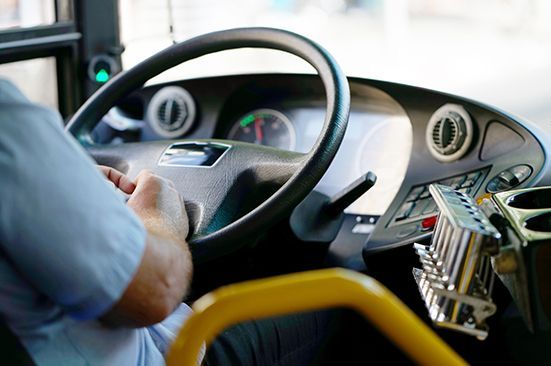 A man is driving a bus with his hands on the steering wheel.