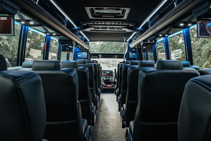 The inside of a bus with lots of seats and televisions.