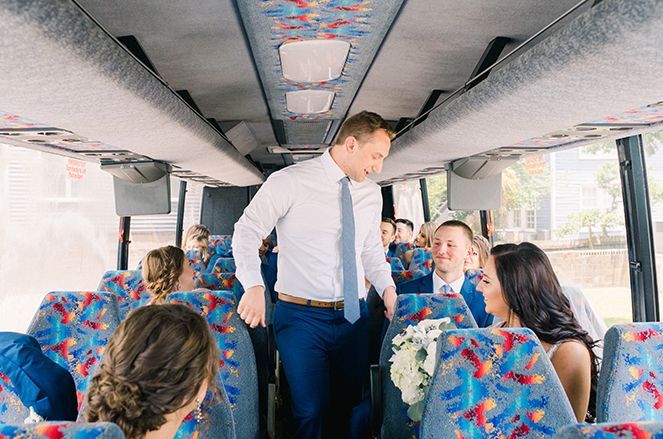 A man is standing in the back of a bus talking to a group of people.