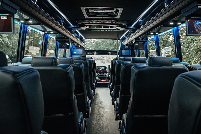 The inside of a bus with lots of seats and televisions.