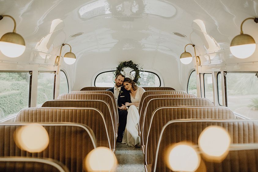 A bride and groom are standing in the back of a bus.