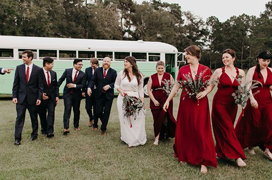 A bride and her bridesmaids are walking in front of a green bus.