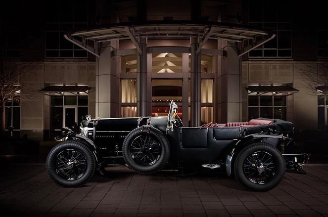 An old car is parked in front of a building at night.