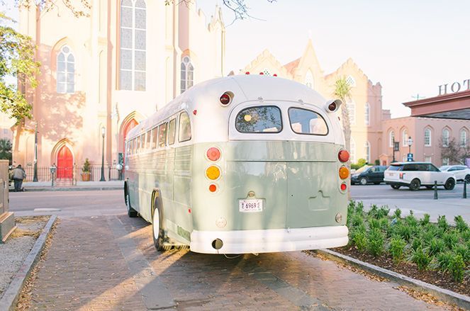 A green and white bus is parked in front of a church.