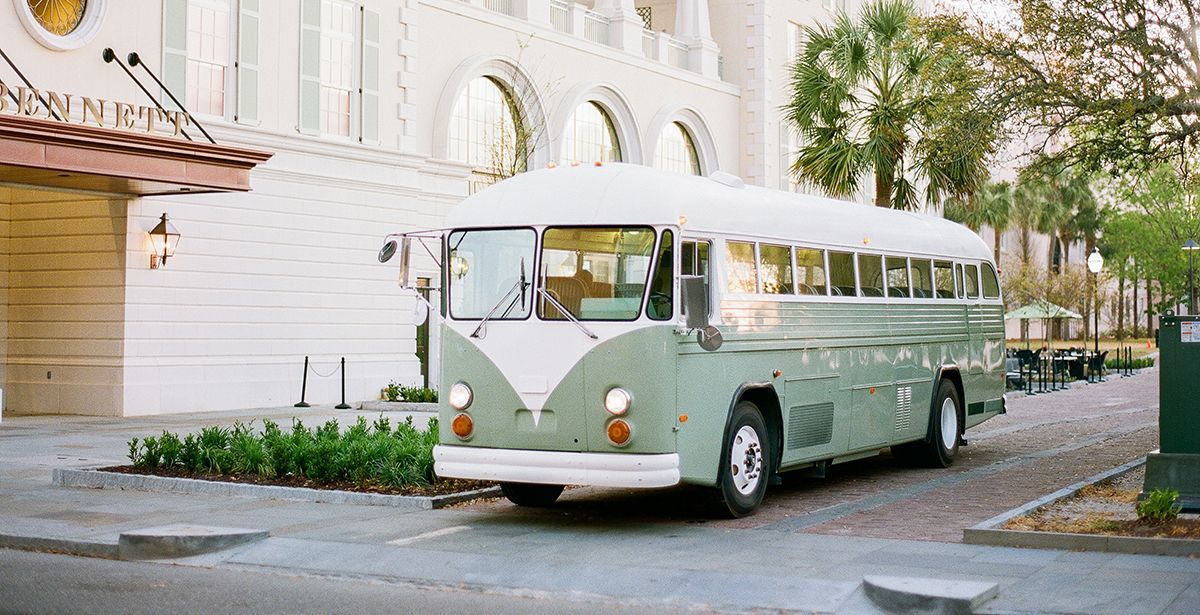 A green and white bus is parked in front of a building.