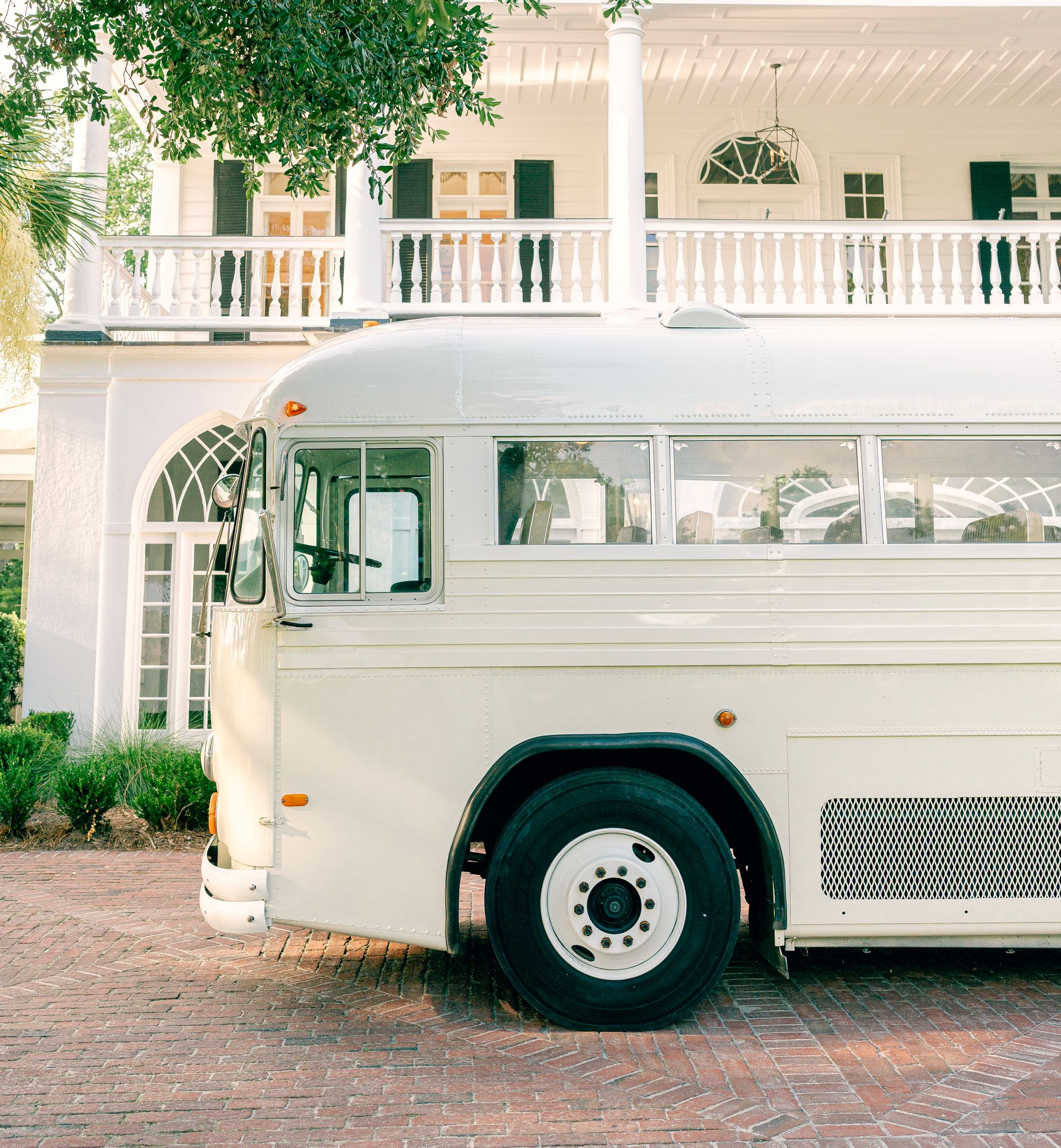 A cream vintage bus is parked on the side of a road.