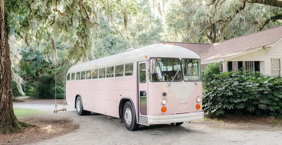 A pink school bus is parked in front of a house.