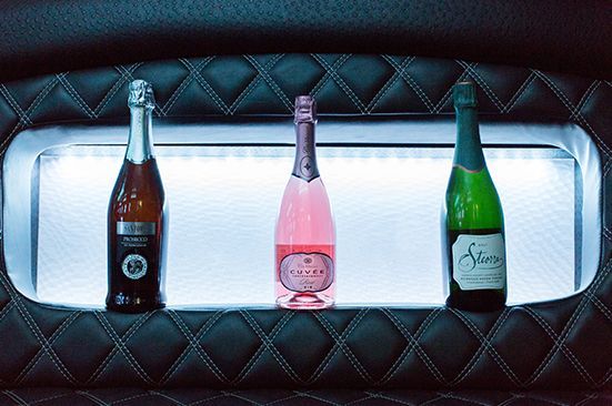 Three bottles of champagne are sitting on a shelf in a car.