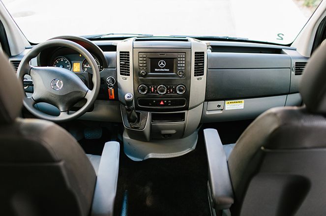 The interior of a van with a steering wheel and a radio.