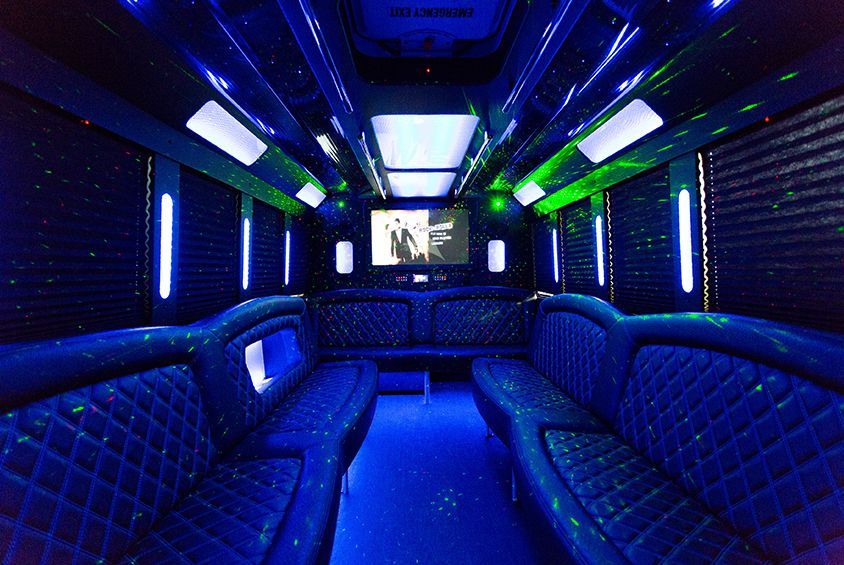 The inside of a limousine with blue lights and a flat screen tv.